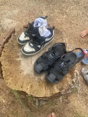Chaussures posées sur un tronc d’arbre avant le parcours du sentier pieds nus du Domaine de Larrous – Domaine de Larrous, Gaujacq (Landes)