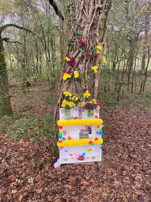 Autel du Día de los Muertos décoré de fleurs colorées au pied d’un arbre en forêt au Sentier Pieds Nus – Domaine de Larrous, Gaujacq (Landes)